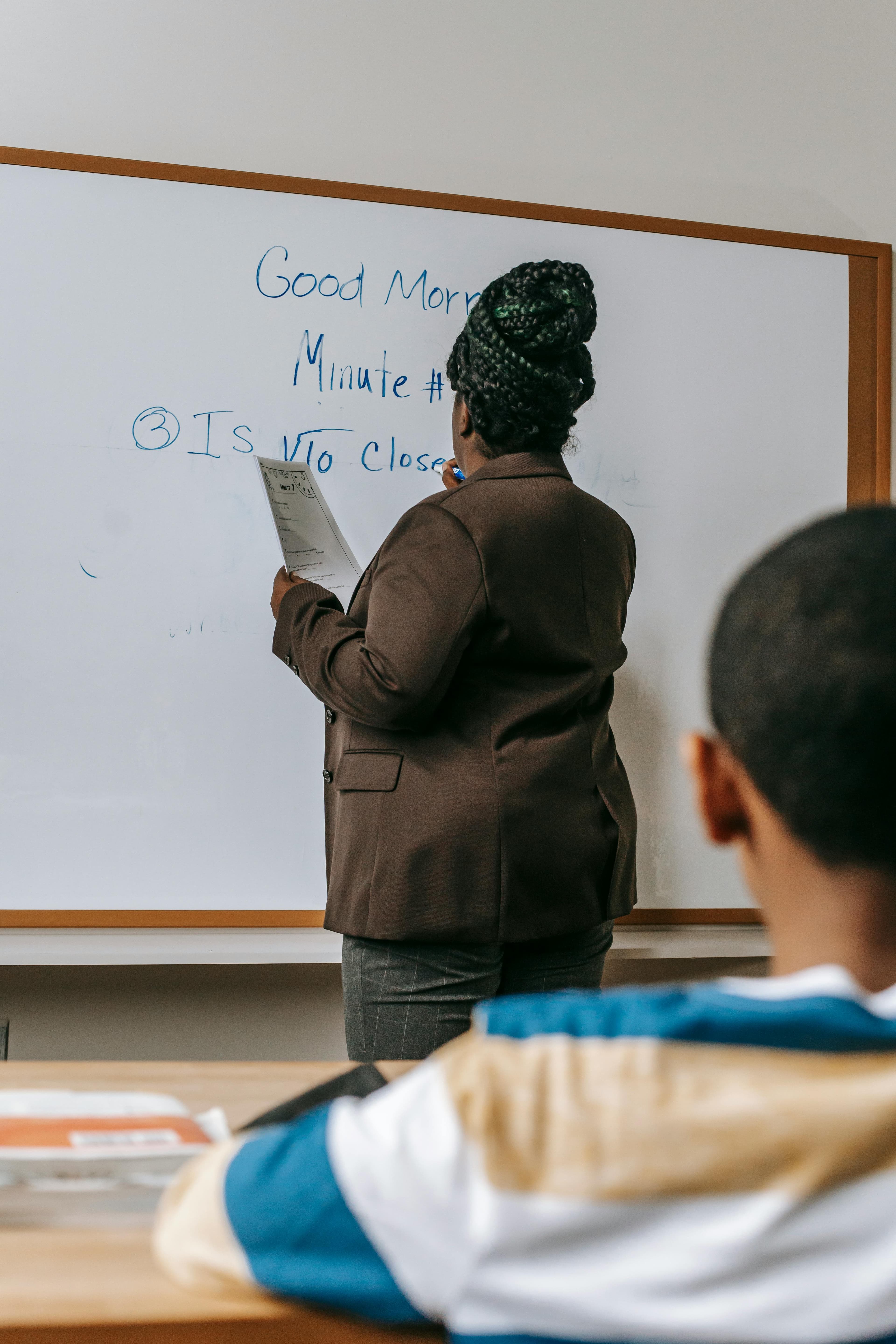 A trainer writing on a classroom whiteboard during lesson planning