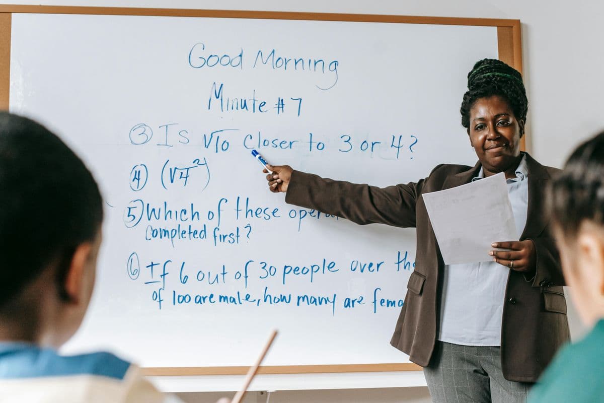 A trainer pointing at tasks on a classroom whiteboard