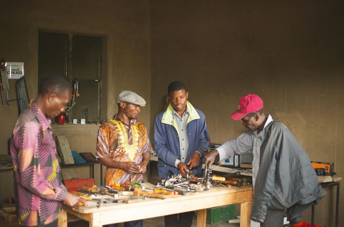 Trainees collaborating around tools in an African vocational workshop