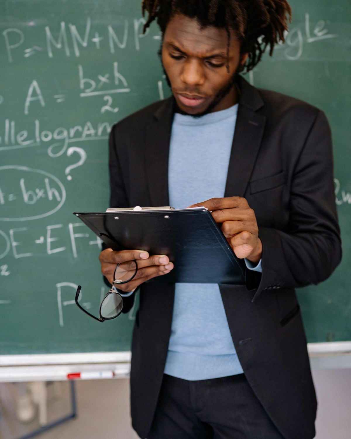 A trainer holding a clipboard in a classroom