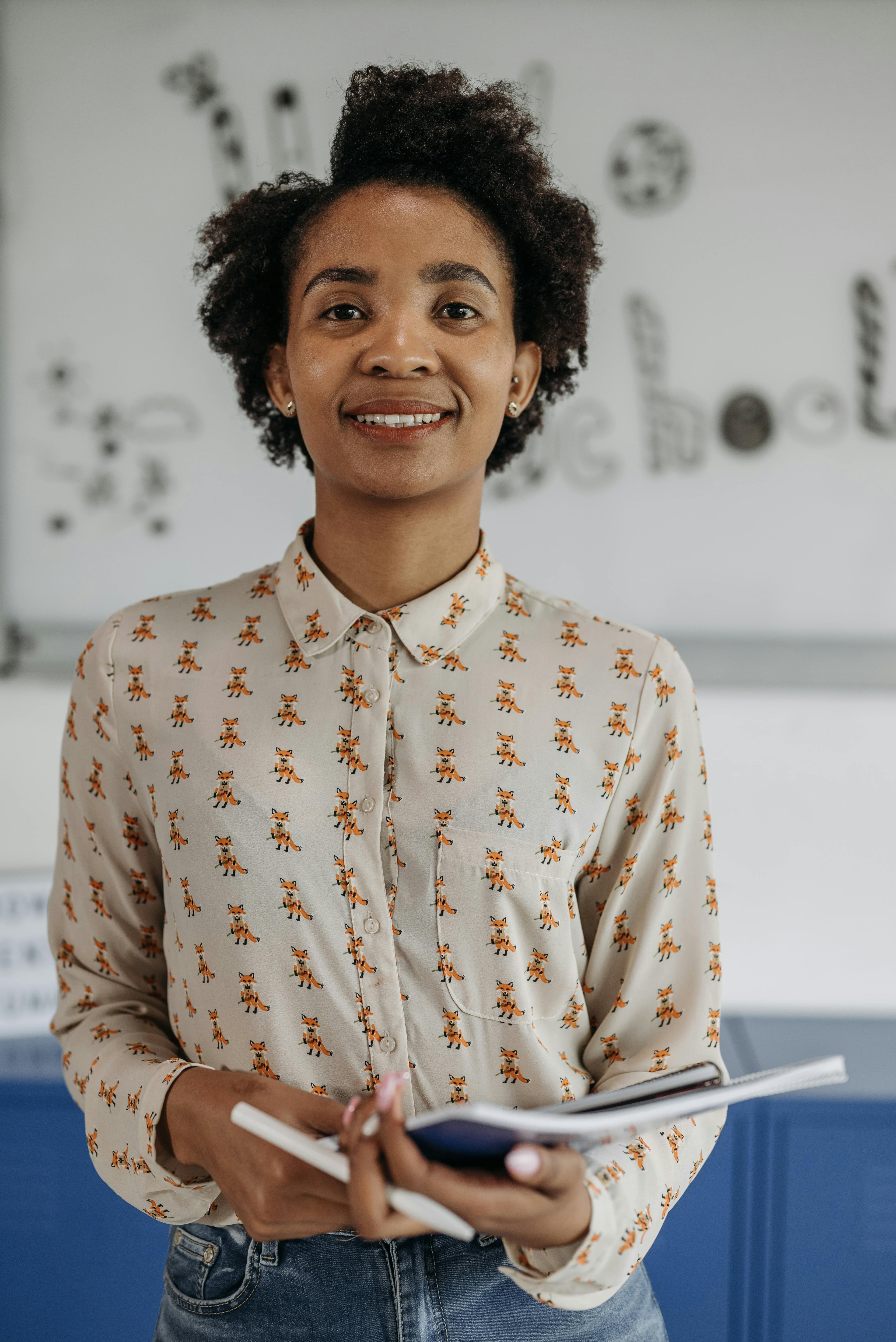 A teacher holding a notebook in a classroom during lesson preparation