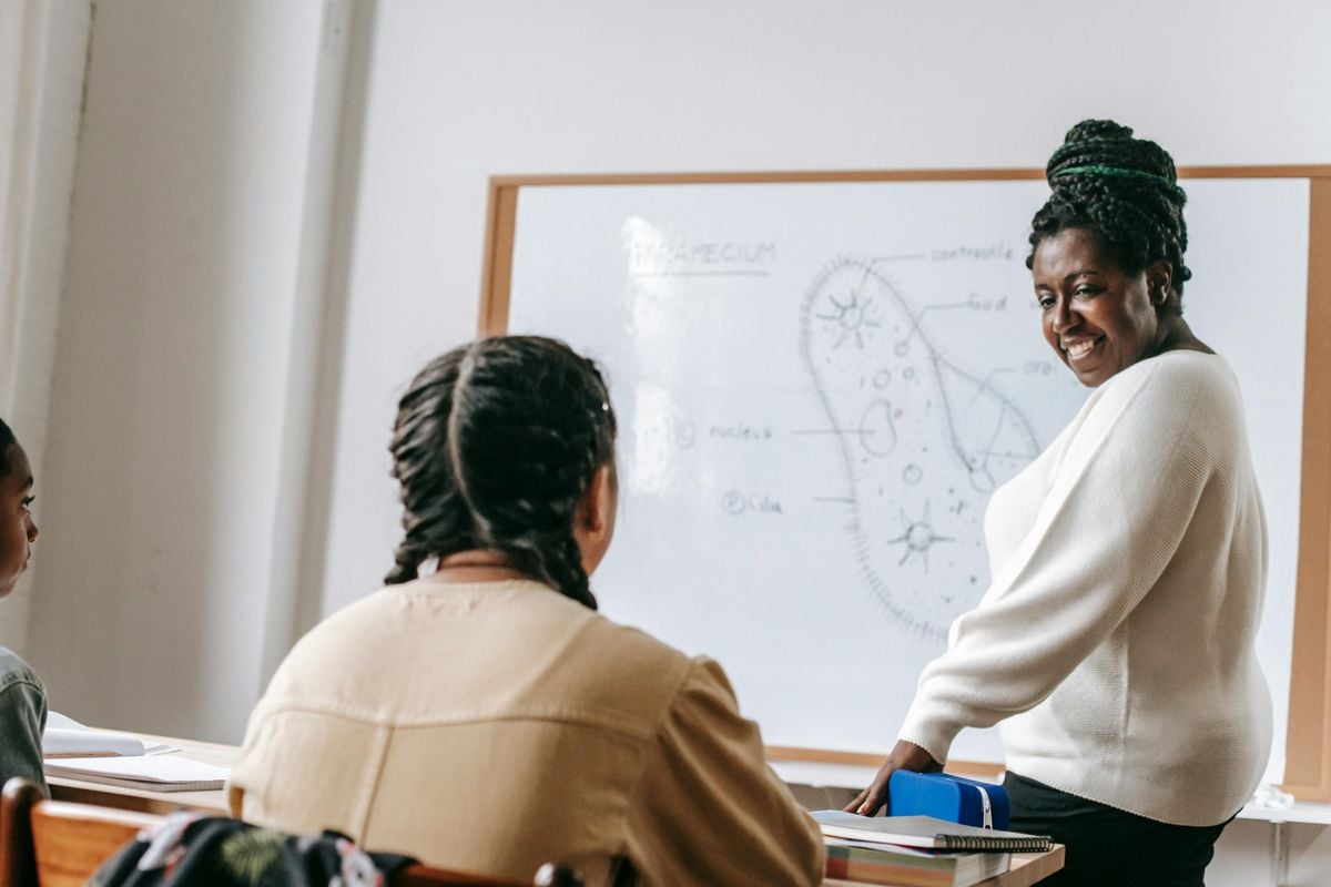 A trainer teaching learners in a classroom using a whiteboard