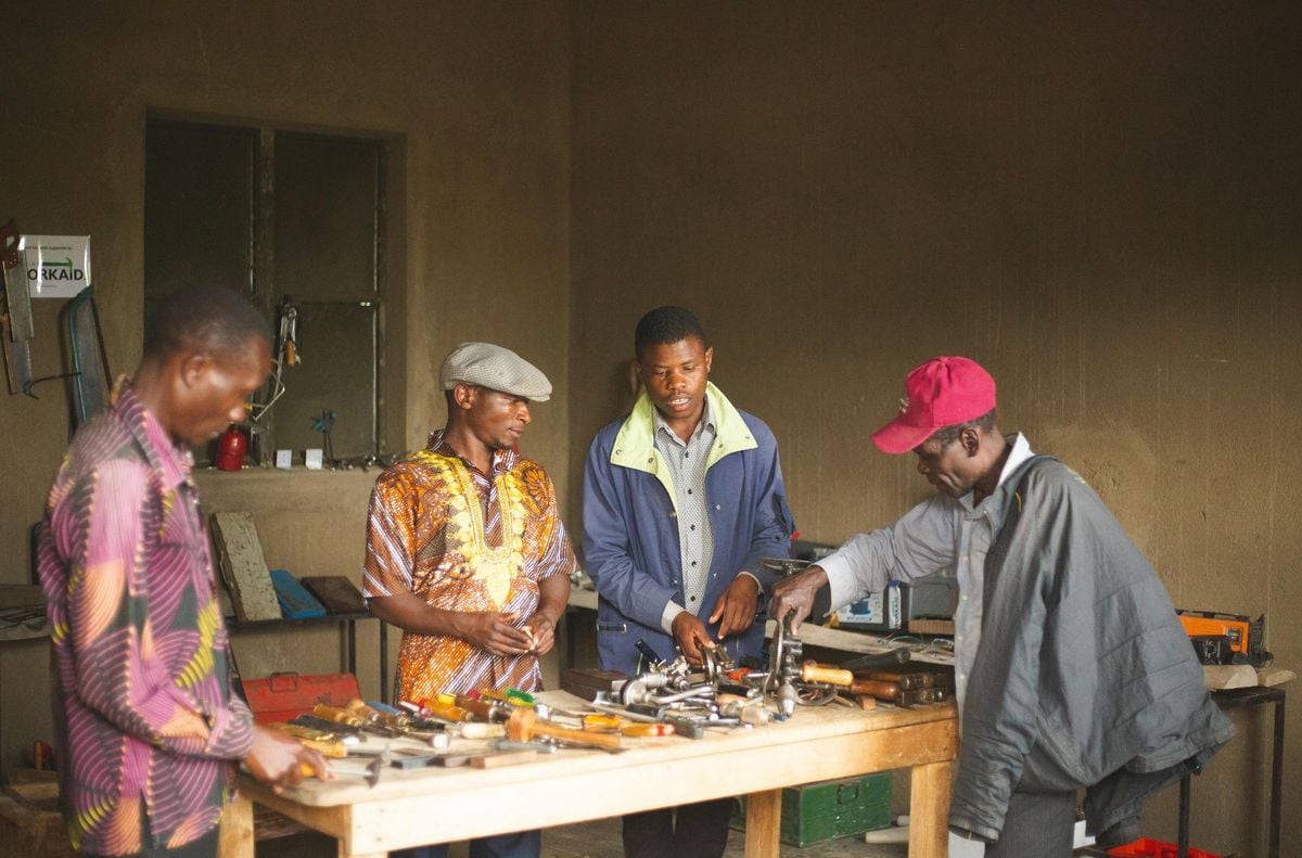 Trainees collaborating around tools in an African vocational workshop